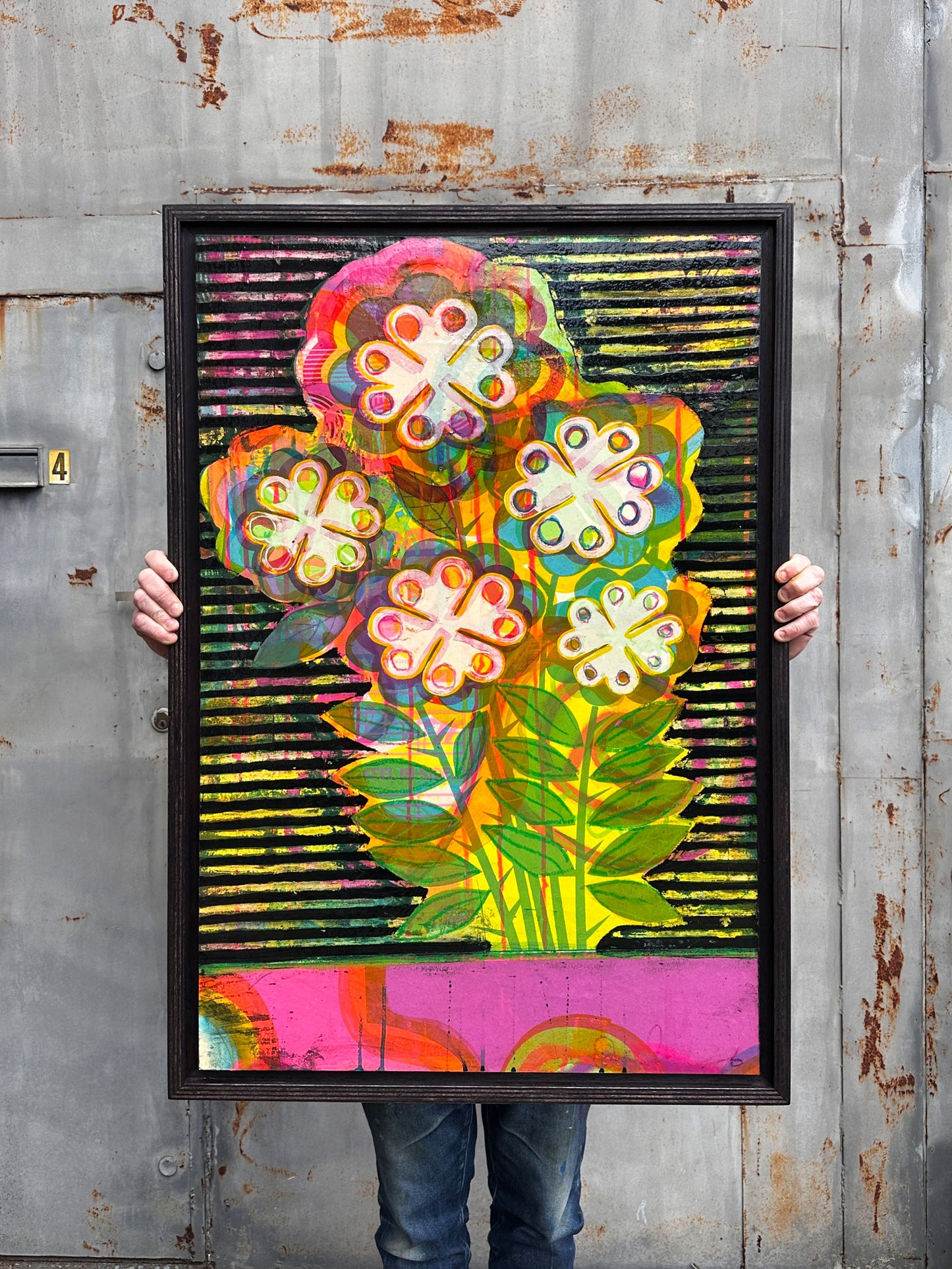 Cowabunga original mixed media artwork by Oli Fowler, framed in dark stained birch, fluorescent pink, yellow and green pop flowers over a black and yellow striped background with a pink stripe at the base