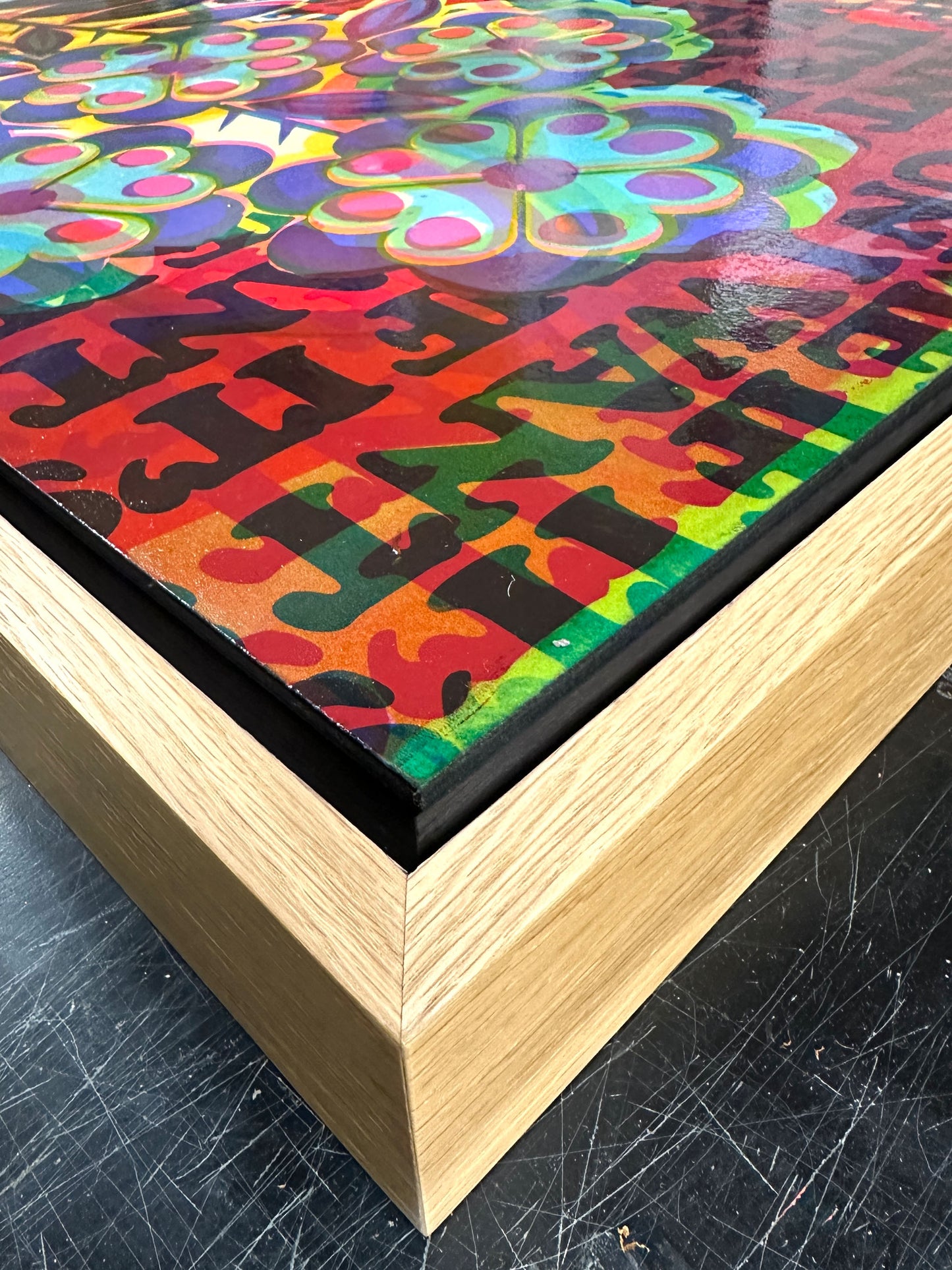Colorful abstract artwork with a wooden frame on a textured surface